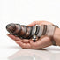 Hand holding the smoke-tinted vibrating finger glove to demonstrate the size, shape, and flexible textured design.